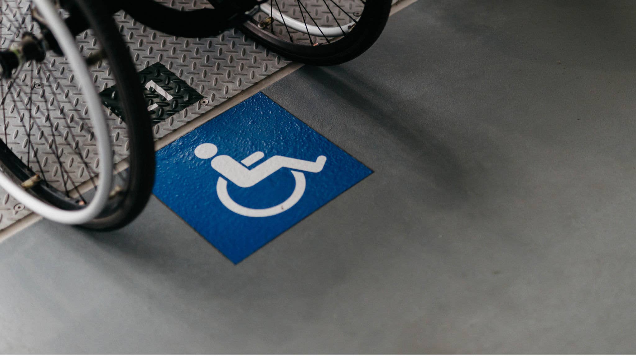 A wheelchair logo painted on the ground with two chair of a wheelchair in the picture