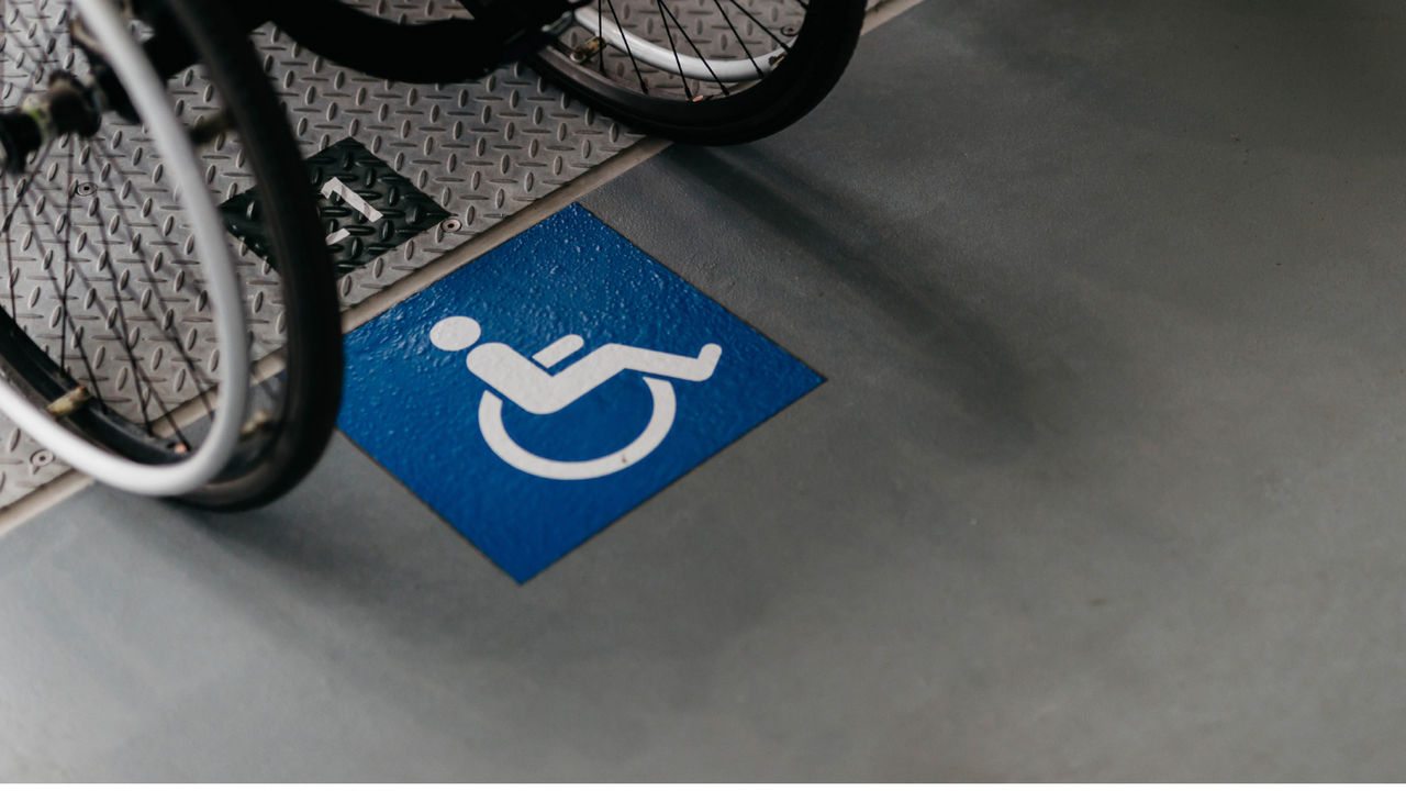 A wheelchair logo painted on the ground with two chair of a wheelchair in the picture